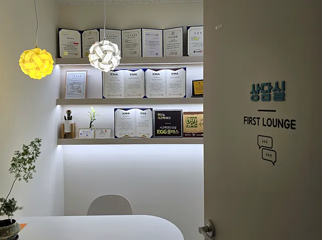 원장 자격증과 학원 인증서가 놓인 선반, 둥근 탁자가 있는 상담실